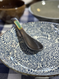 Blue patterned plate with a black spoon on a checkered tablecloth