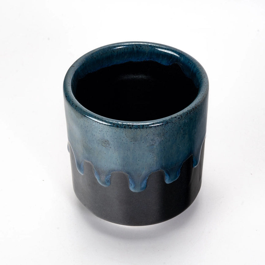 Blue and black ceramic cup with textured design on a white background