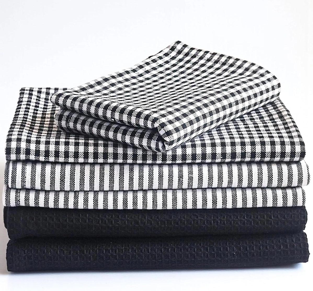 Stack of folded black and white checkered, striped, and textured towels on a white background