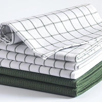 Stack of folded checkered and solid color cloths on a white background