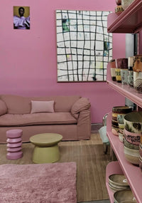 Living room with pink walls, furniture, and decor including a shelf with vases.