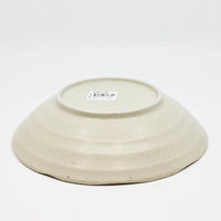 Beige ceramic bowl with a visible brand label on a white background