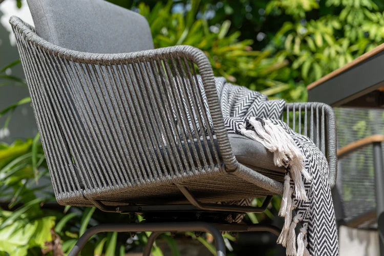 Woven chair with a blanket draped over it in an outdoor setting