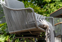 Woven chair with a blanket draped over it in an outdoor setting