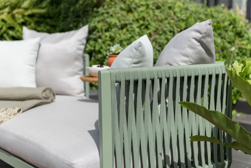 Outdoor seating area with green chair and white cushions in a garden setting