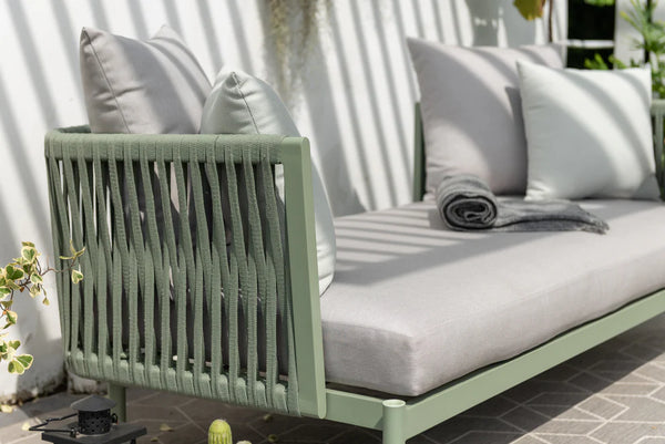 Outdoor sofa with green frame and white cushions on a patio