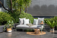 Green outdoor daybed with pillows on black tiles
