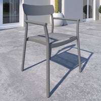 Gray chair on a concrete surface with a building and plants in the background
