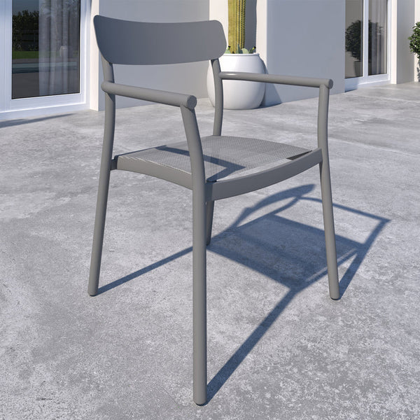 Gray chair on a concrete surface with a building and plants in the background