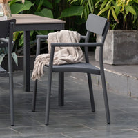 Gray outdoor chair with a blanket draped over it on a stone patio.