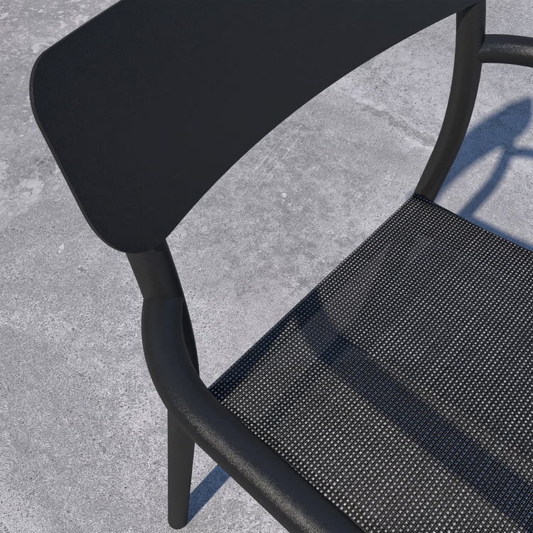 Black metal chair with mesh seat on a concrete surface