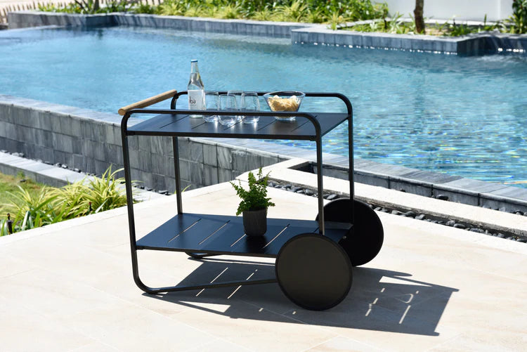 Black metal serving cart with a grey top by a poolside