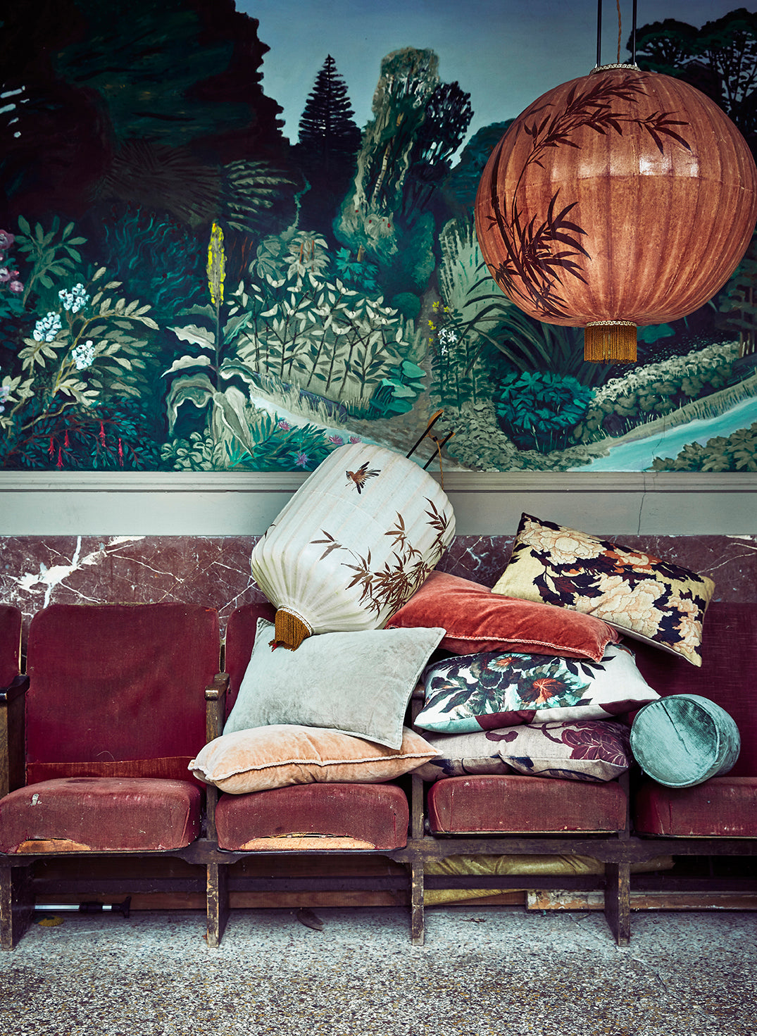 Decorative sofa with patterned cushions against a mural of a forest scene.