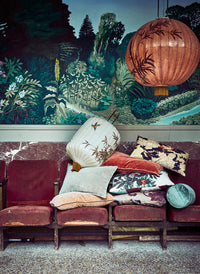 Decorative sofa with patterned cushions against a mural of a forest scene.