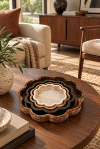 set of four nesting scalloped wooden plates in various colors of wood on a dark brown table in a living room