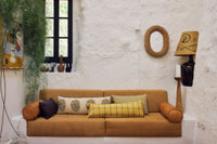 brown coach with pillows against white wall with texture