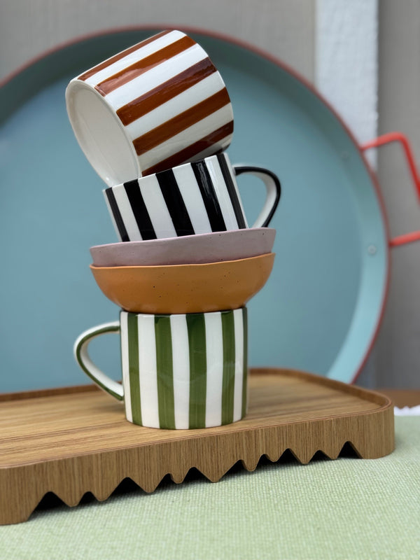 Stack of colorful striped mugs on a wooden tray with a blurred background