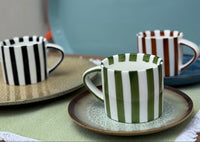 Set of ceramic cups with striped patterns on a table.