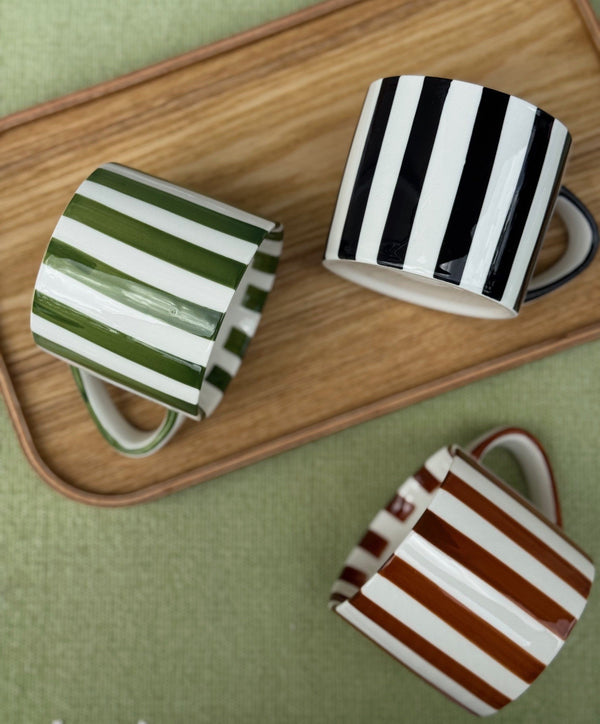 Three striped mugs on a wooden tray with a green background
