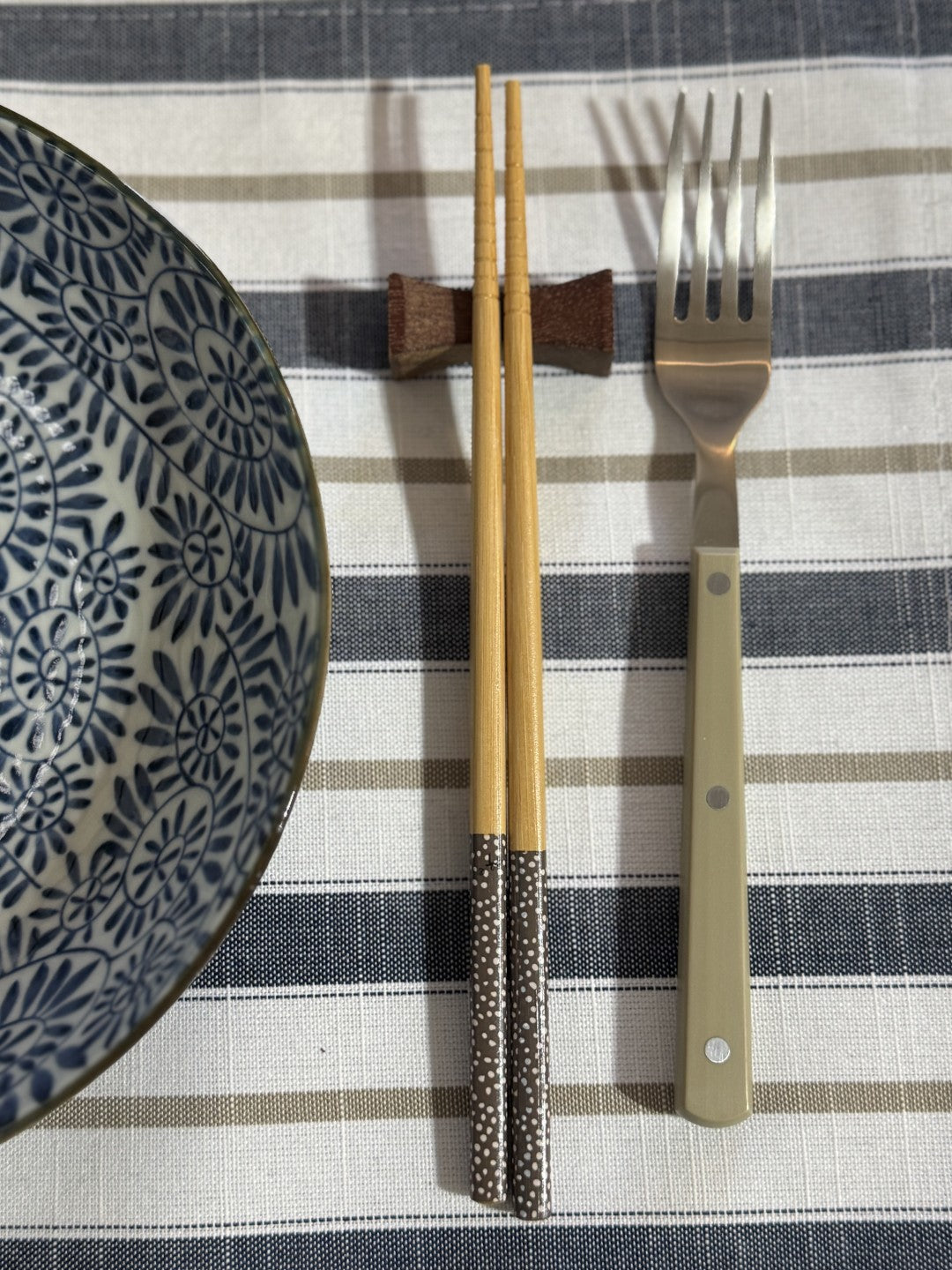 Pacifica dinnerware set with bowl, chopsticks, and fork on a striped tablecloth