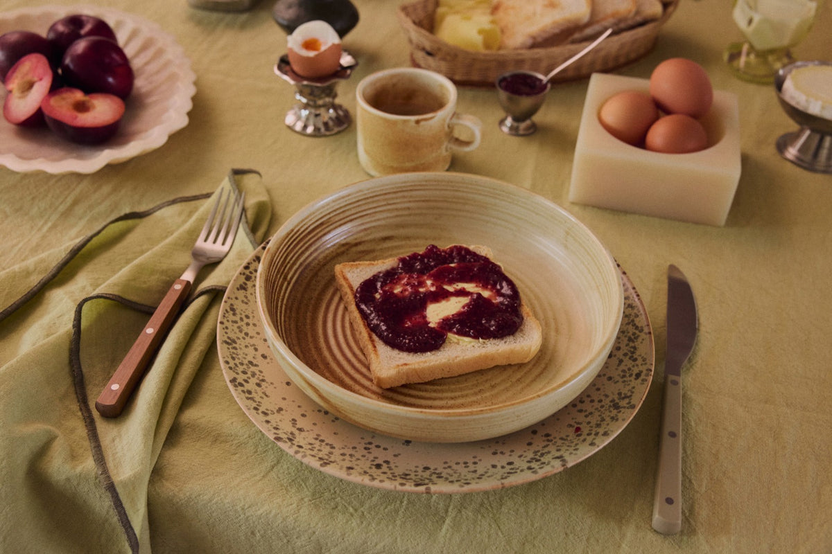 Breakfast scene with toast, jam, and eggs on a tablecloth.