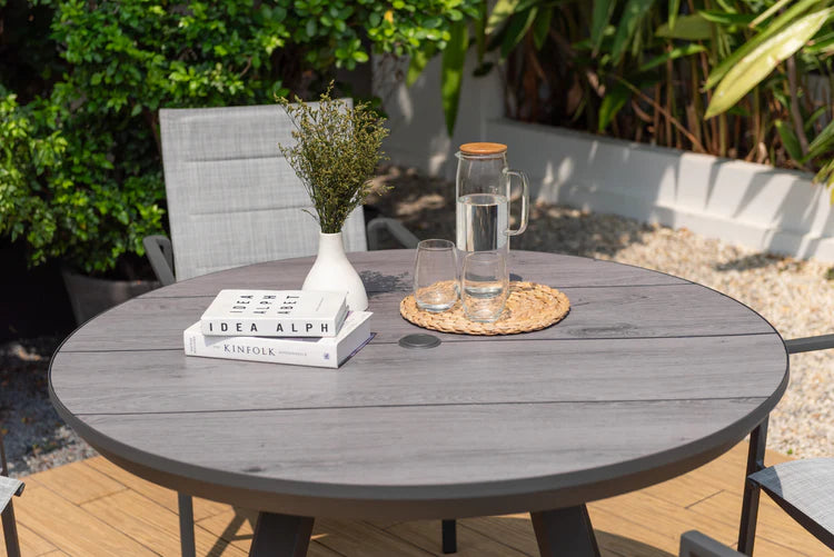 Round outdoor table with books, glasses, and a pitcher on a patio