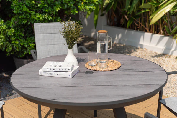 Round outdoor table with books, glasses, and a pitcher on a patio