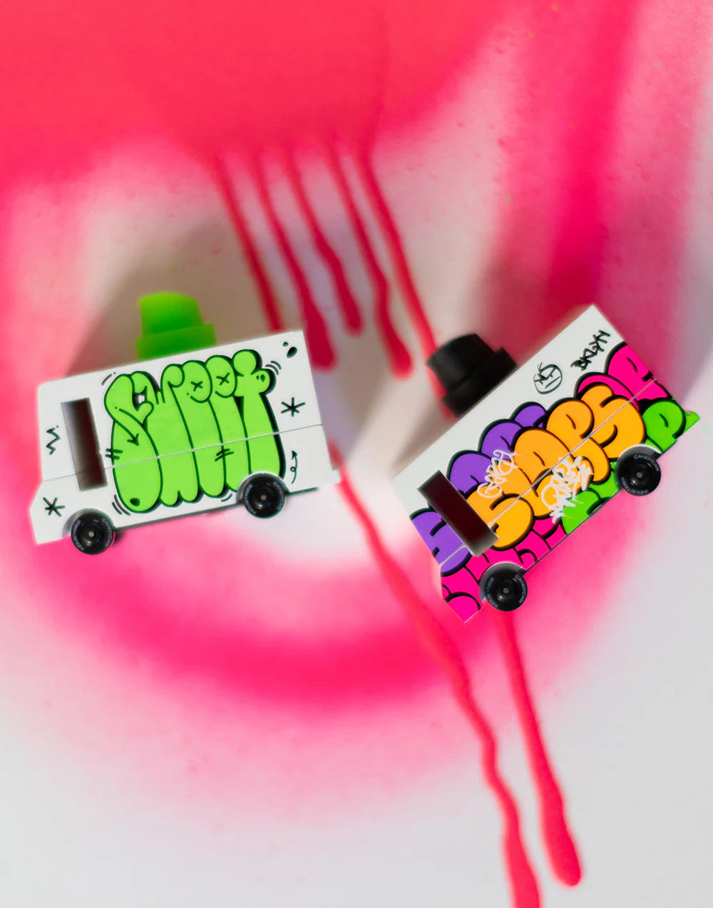 Two colorful design wooden cars with cartoon designs on a pink and white background