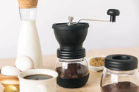 Hand coffee grinder with coffee beans on a wooden table