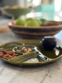 Green ceramic plate with nuts on a marble surface, blurred background