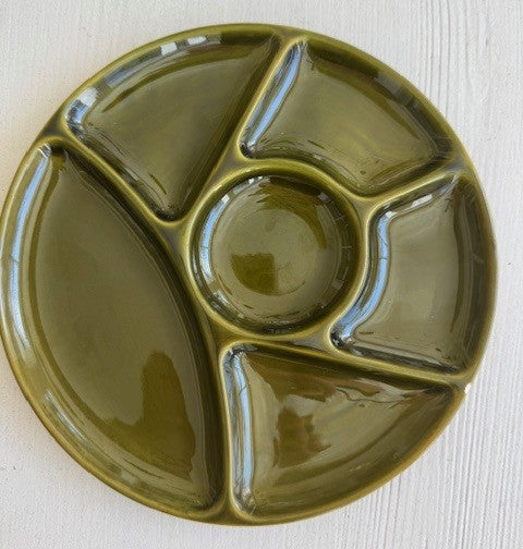 Green ceramic plate with divided sections on a light wooden surface