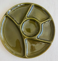 Green ceramic plate with divided sections on a light wooden surface