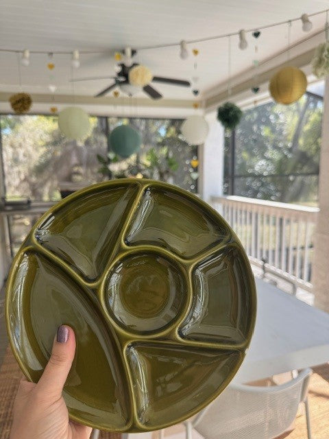 Green ceramic plate with geometric design held by a hand indoors.