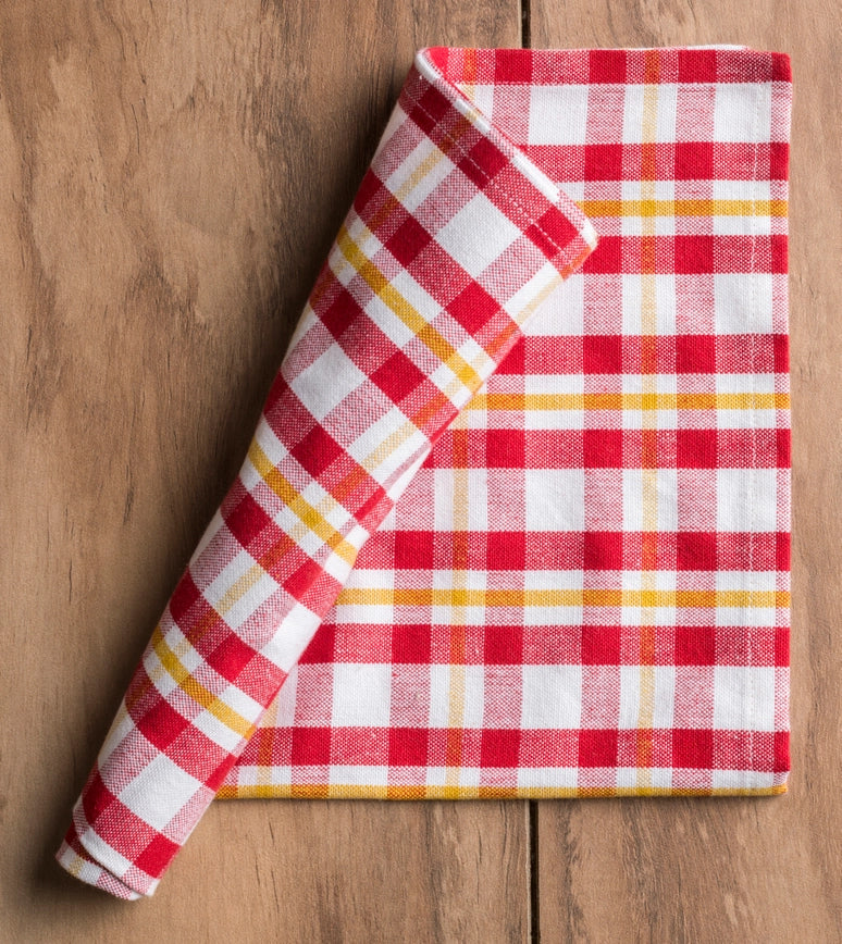 Folded red and white checkered cloth  napkin on a wooden surface