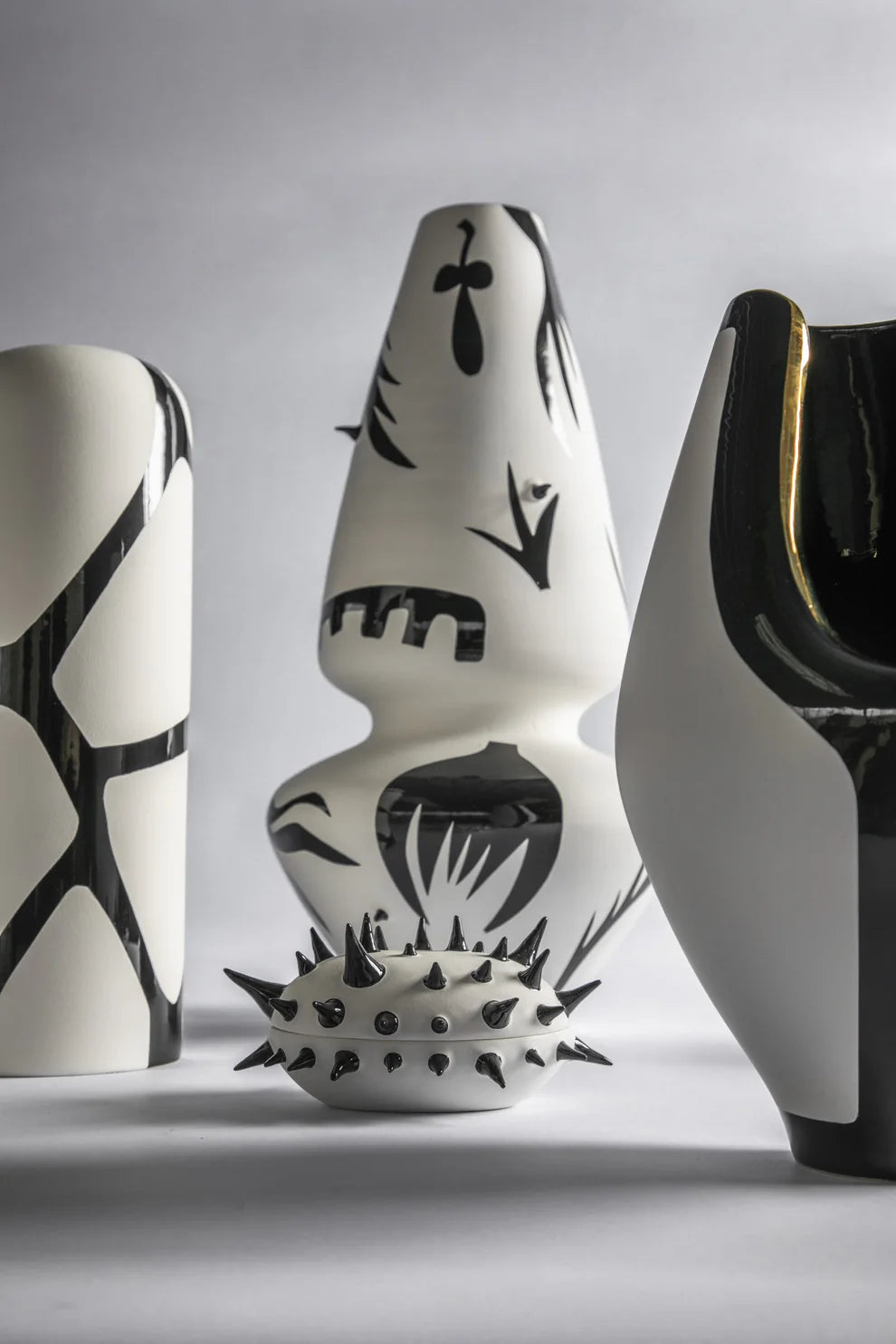 Three ceramic vases with black abstract patterns on a gray background