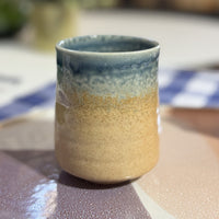 Ceramic mug with blue and beige gradient on a blurred background