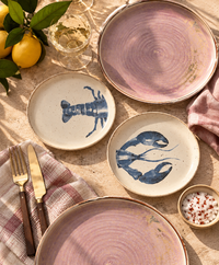 plates with head and teal of lobster on an outdoor dining table with pink dinner plates