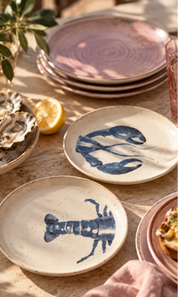 plates with head and teal of lobster on an outdoor dining table with pink dinner plates