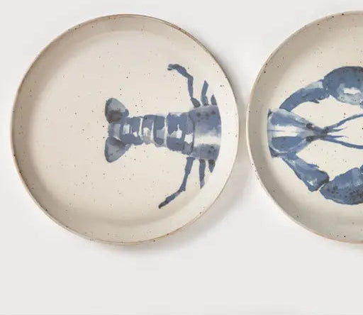 Two round speckled ceramic plates with blue lobster illustrations, shown on a clean white background.