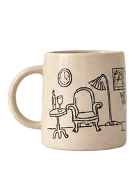 A cream-colored ceramic mug featuring a black line art illustration of a cozy living room scene with an armchair, side table, lamp, and clock.