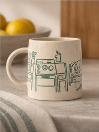 beige mug with a green illustration of a kitchen interior
