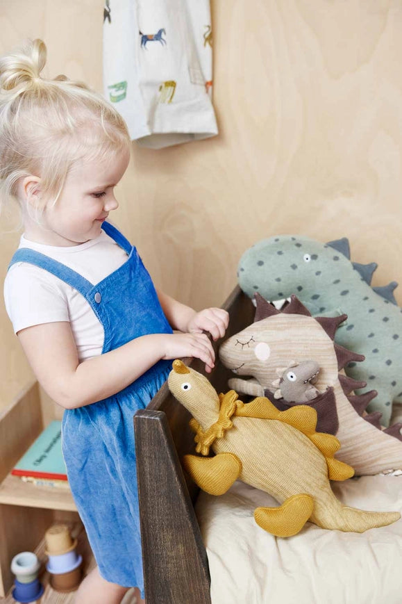 Child playing with plush toys on a bed in a bedroom setting