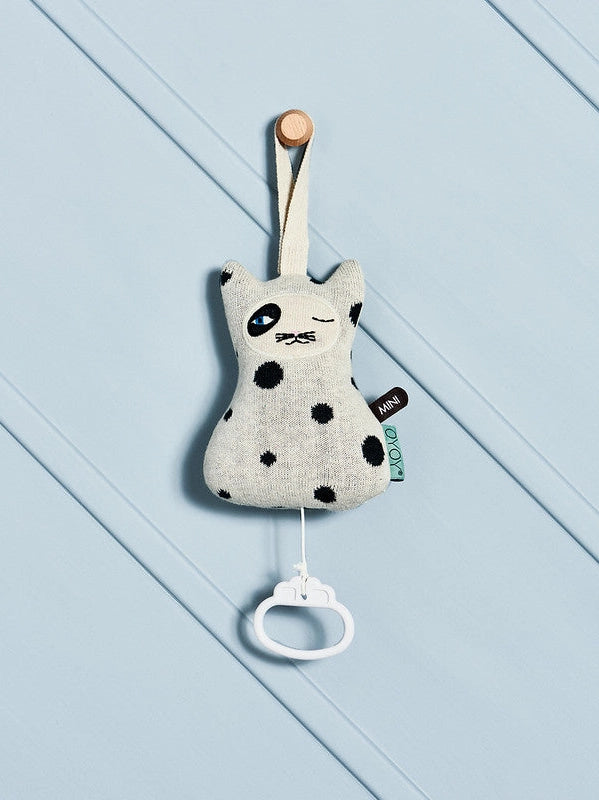 Plush toy with black spots on a light blue wooden background