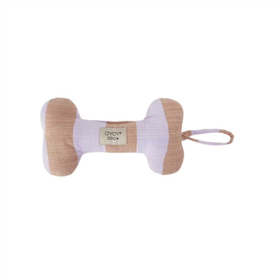 A bone-shaped dog toy made of textured fabric in beige and pale lavender, featuring a small woven label that reads 'OYOV zoov' and a matching fabric loop on the side, set against a plain white background.