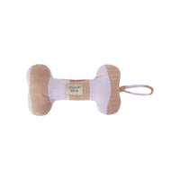 A bone-shaped dog toy made of textured fabric in beige and pale lavender, featuring a small woven label that reads 'OYOV zoov' and a matching fabric loop on the side, set against a plain white background.