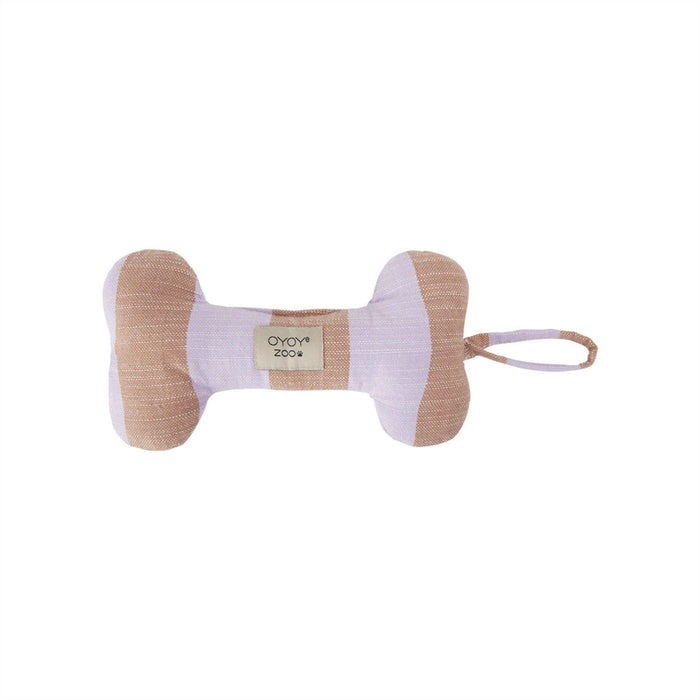 A bone-shaped dog toy made of textured fabric in beige and pale lavender, featuring a small woven label that reads 'OYOV zoov' and a matching fabric loop on the side, set against a plain white background.