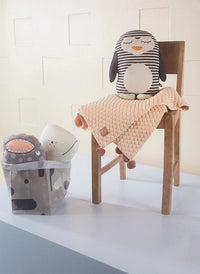 Plush toys and a pink blanket on a chair against a white wall