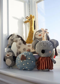 Collection of plush toys shaped like animals on a windowsill with a view of the sky.