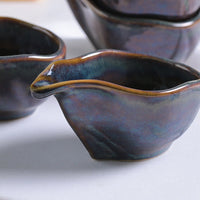 Ceramic gravy boat with a dark blue glaze on a white surface