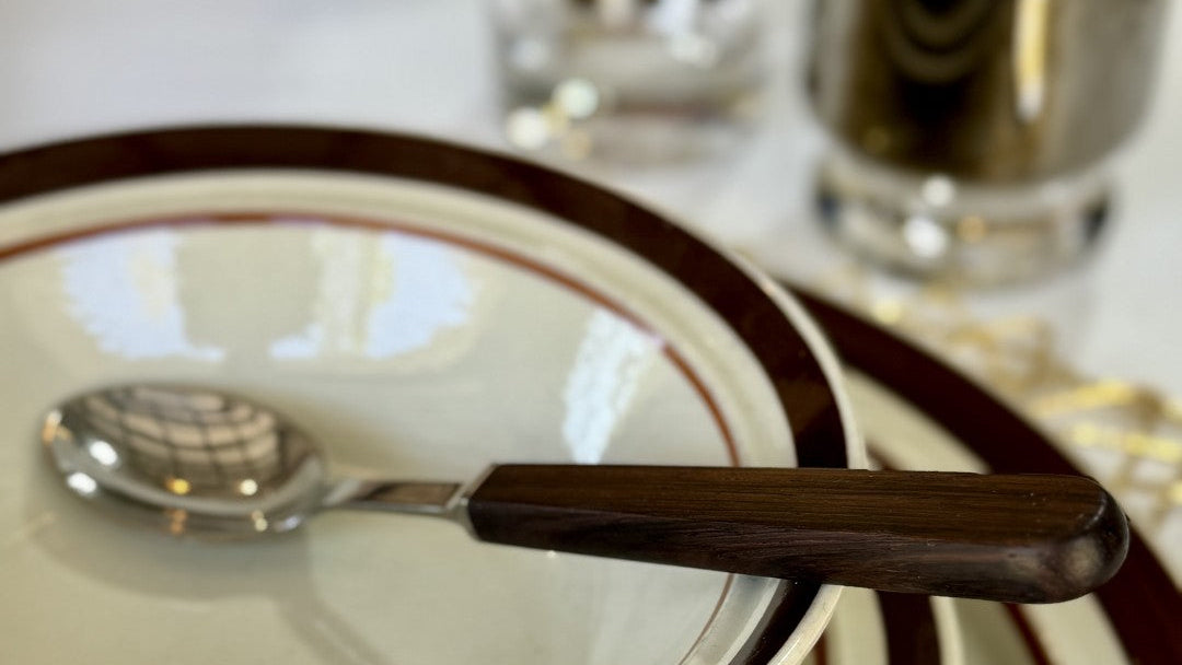 Stack of plates with a spoon on top, placed on a checkered tablecloth.